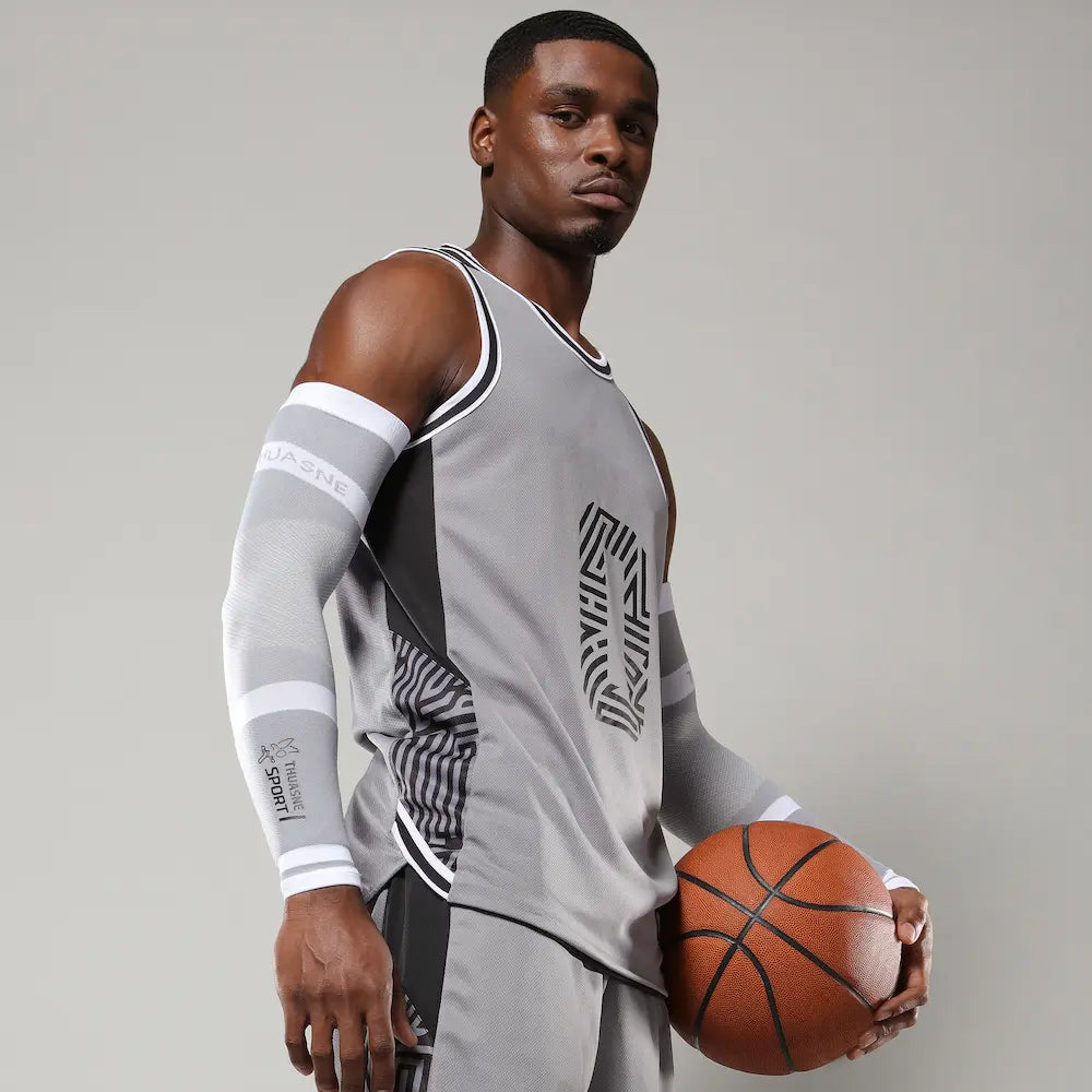 Basketteur équipé de manchettes de compression gris clair et blanc THUASNE SPORT avec ballon