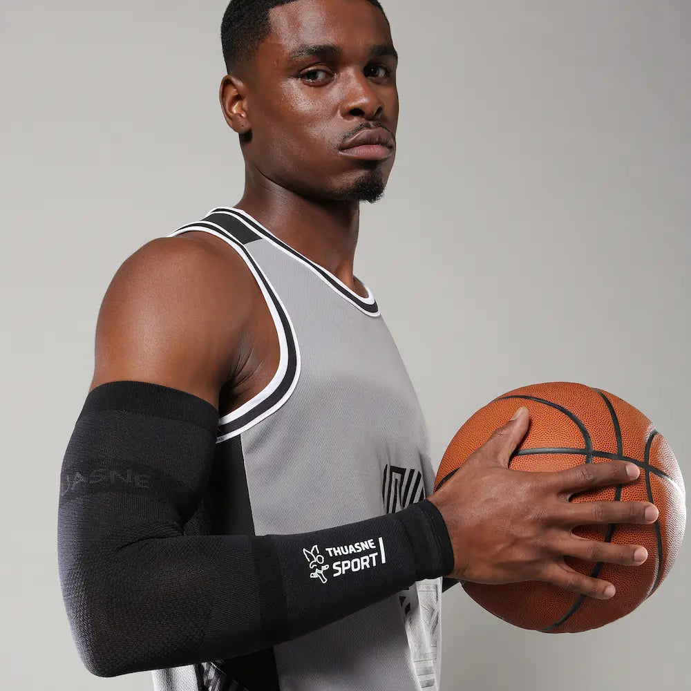 Basketteur portant les manchettes de compression noires THUASNE SPORT et tenant un ballon