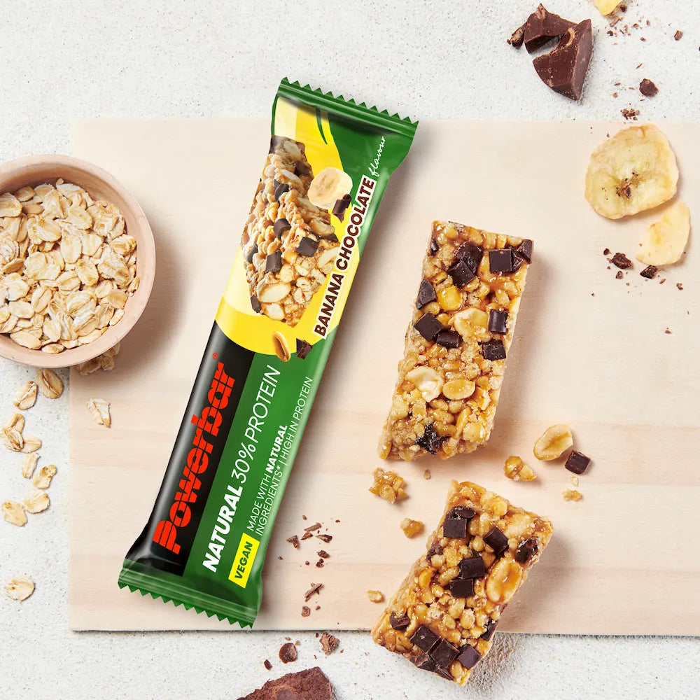 Barre vegan Powerbar Natural Protein Banane-chocolat ouverte avec morceaux de banane, chocolat, cacahuètes et flocons d'avoine