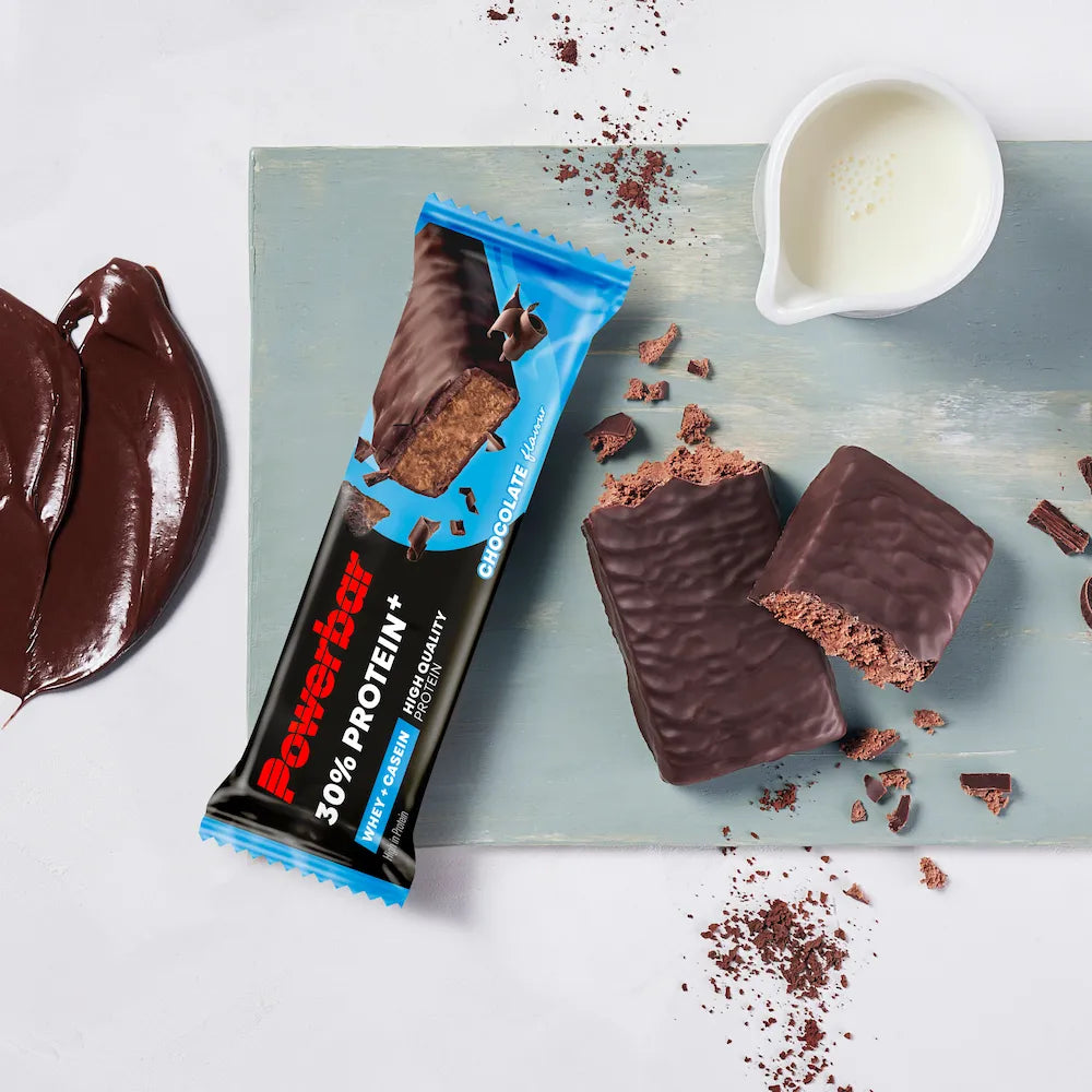 Barre protéinée Powerbar Protein+ 30% Chocolat ouverte et coupée avec enrobage chocolaté, morceaux de chocolat et lait