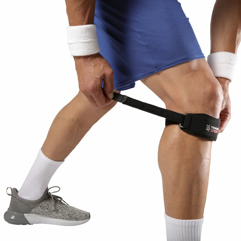 Sportif ajustant la sangle du bandage rotulien Thuasne Sport sous le genou