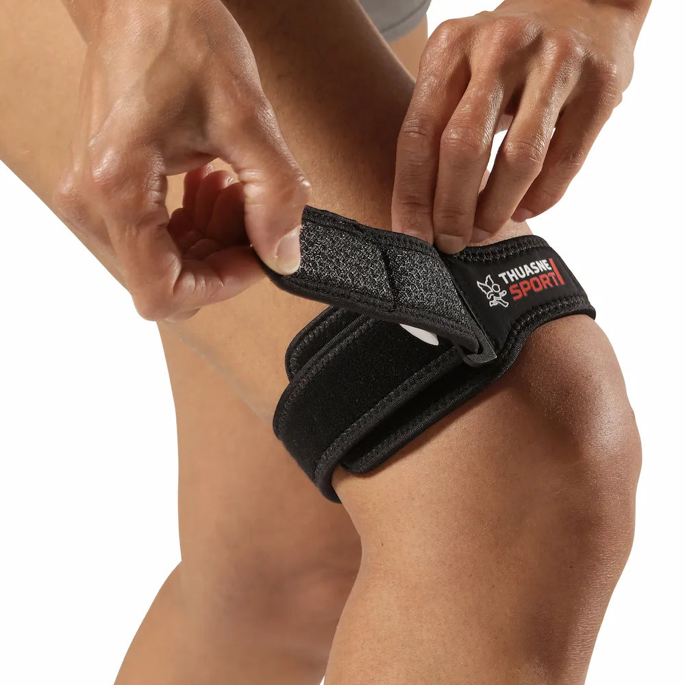 Sportive ajustant la sangle de serrage de la bandelette ilio-tibiale TFL Thuasne Sport