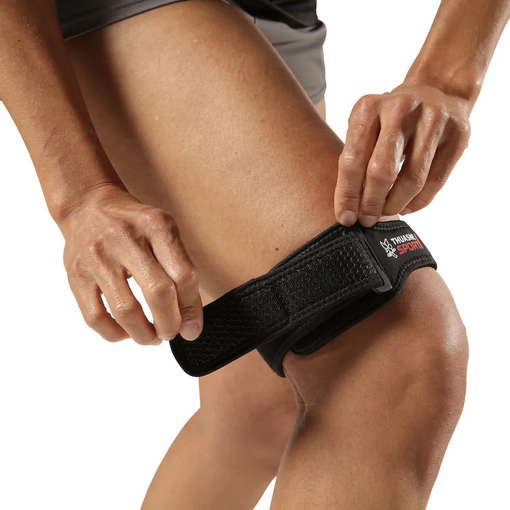 Sportive ajustant une bandelette ilio-tibiale TFL Thuasne Sport au-dessus du genou