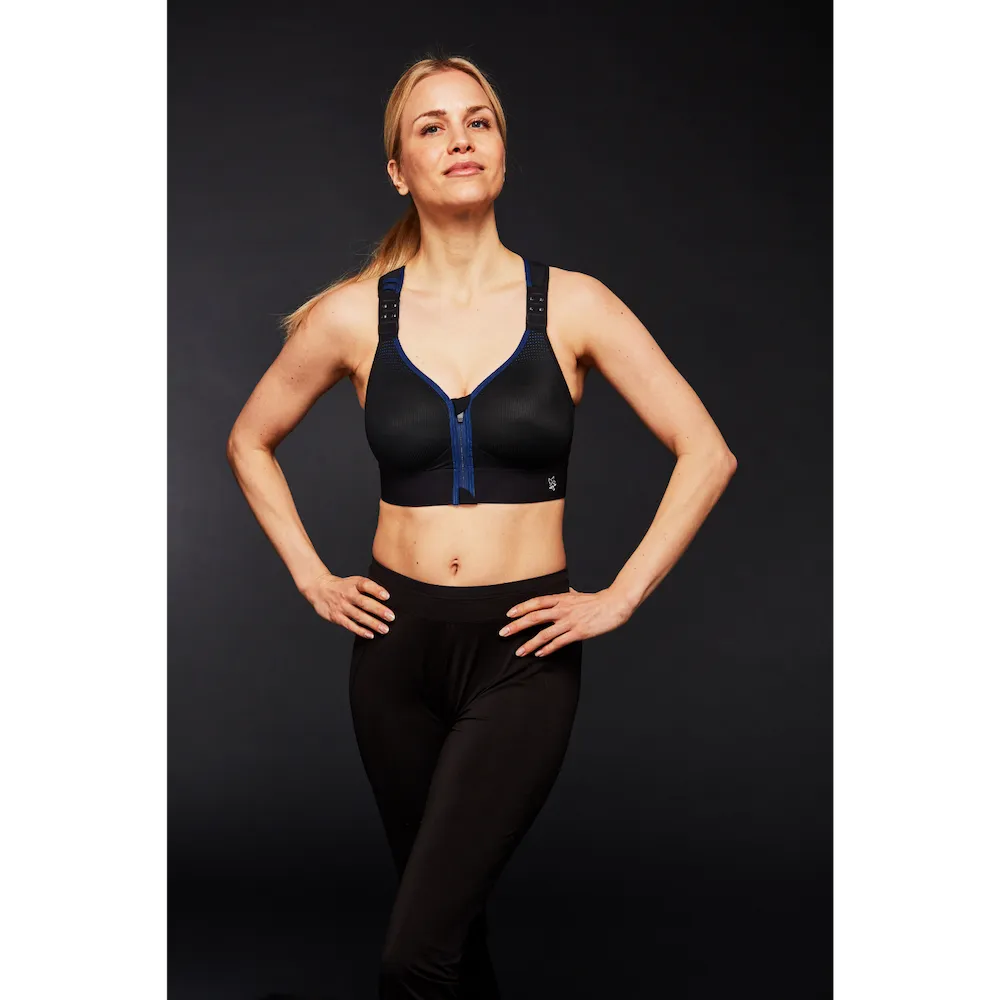 Femme portant la brassière Eaz'ip EVO Thuasne Sport noire sur fond sombre