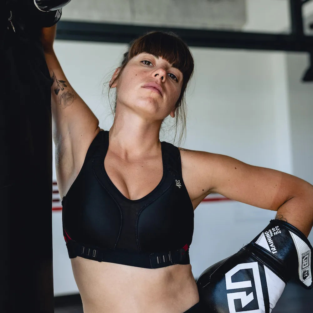 Femme portant la brassière Strapping Bra Thuasne Sport noire pendant un entraînement de boxe