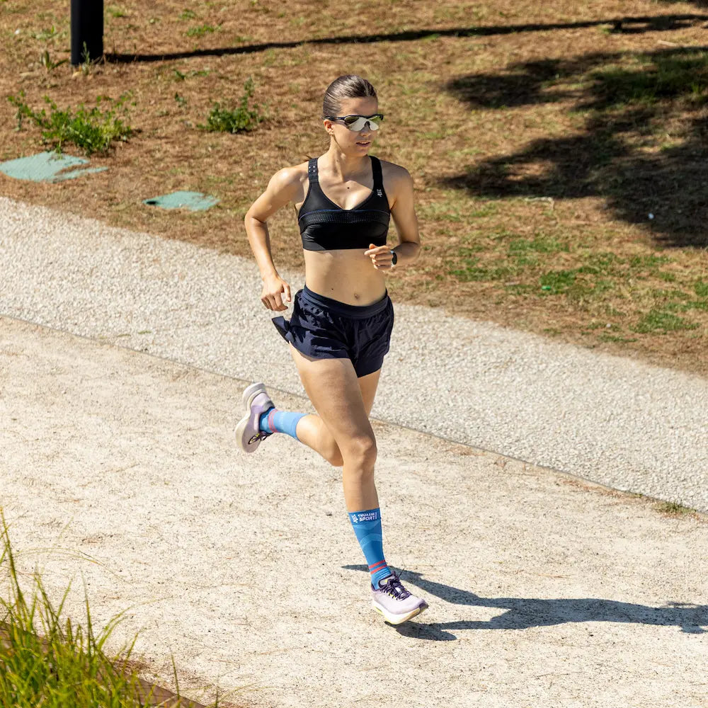 Femme courant avec des chaussettes de compression Mid ACTIV Thuasne Sport bleues
