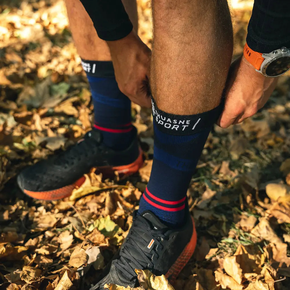 Sportif ajustant ses chaussettes de compression Mid ACTIV Thuasne Sport en forêt