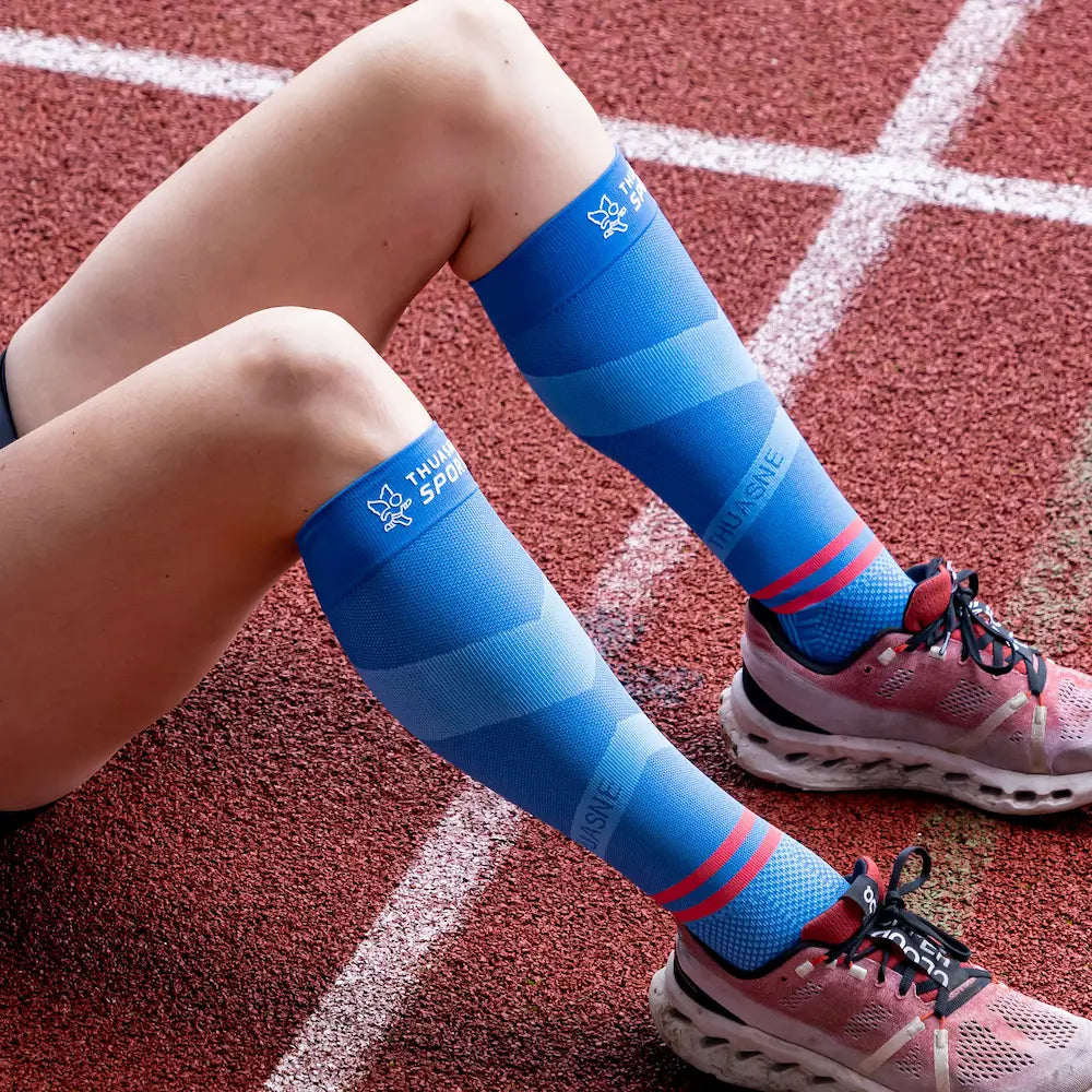 Sportive portant des chaussettes longues de compression ACTIV Thuasne Sport sur une piste