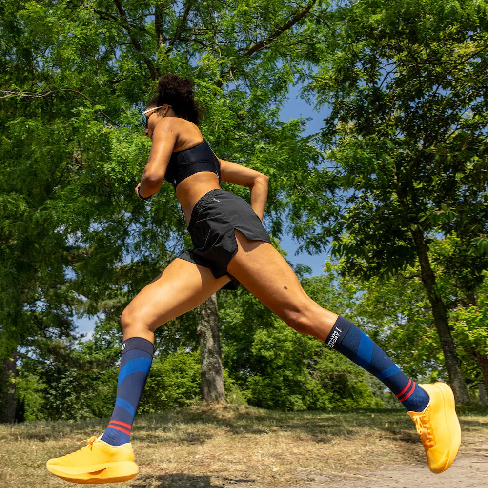 Femme courant avec des chaussettes longues de compression ACTIV Thuasne Sport