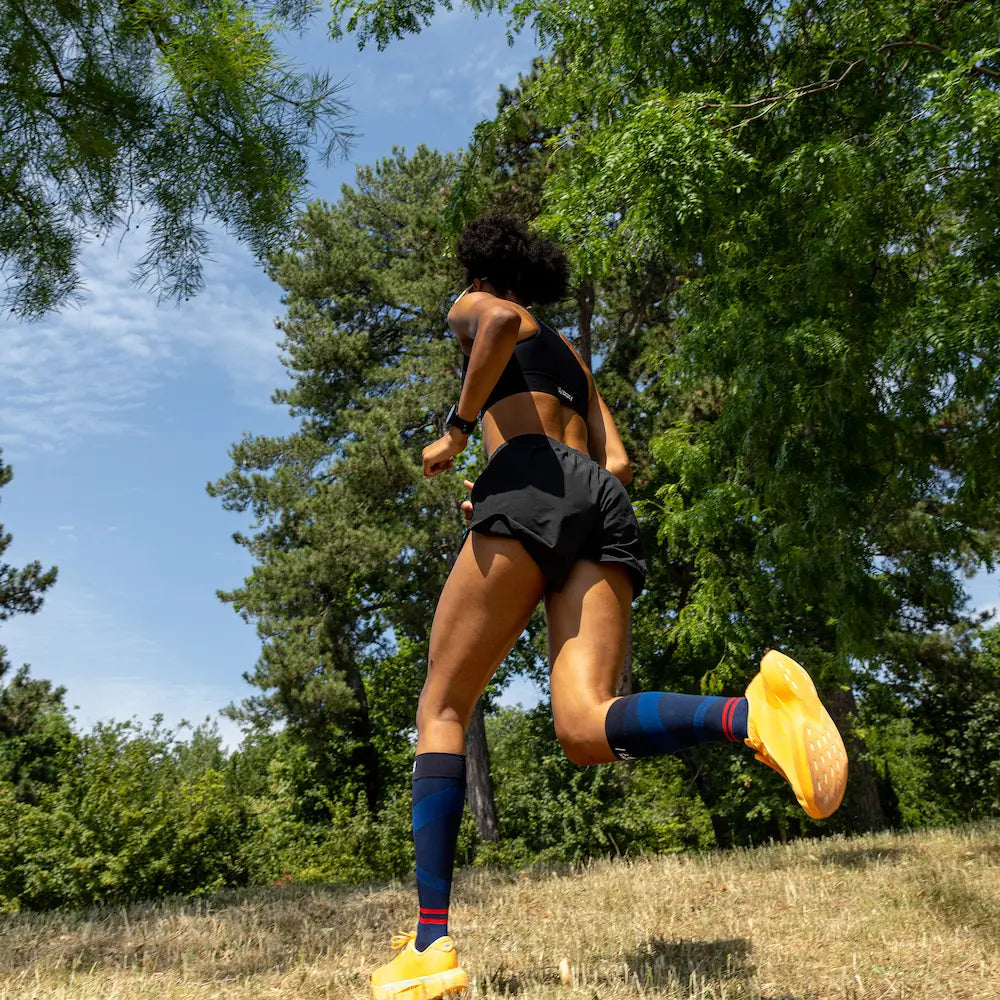 Femme en pleine course portant des chaussettes longues de compression ACTIV Thuasne Sport