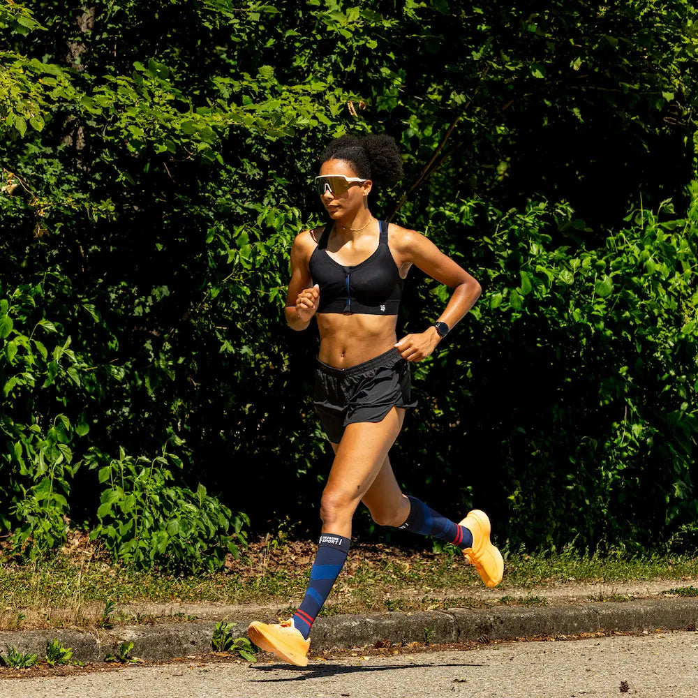 Femme courant en extérieur avec des chaussettes longues de compression ACTIV Thuasne Sport
