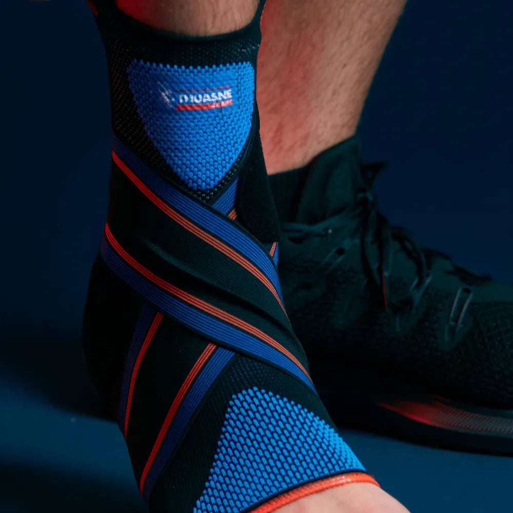 Gros plan sur la chevillère Novelastic Thuasne Sport Stabilité 4 avec sanglage croisé bleu noir et orange