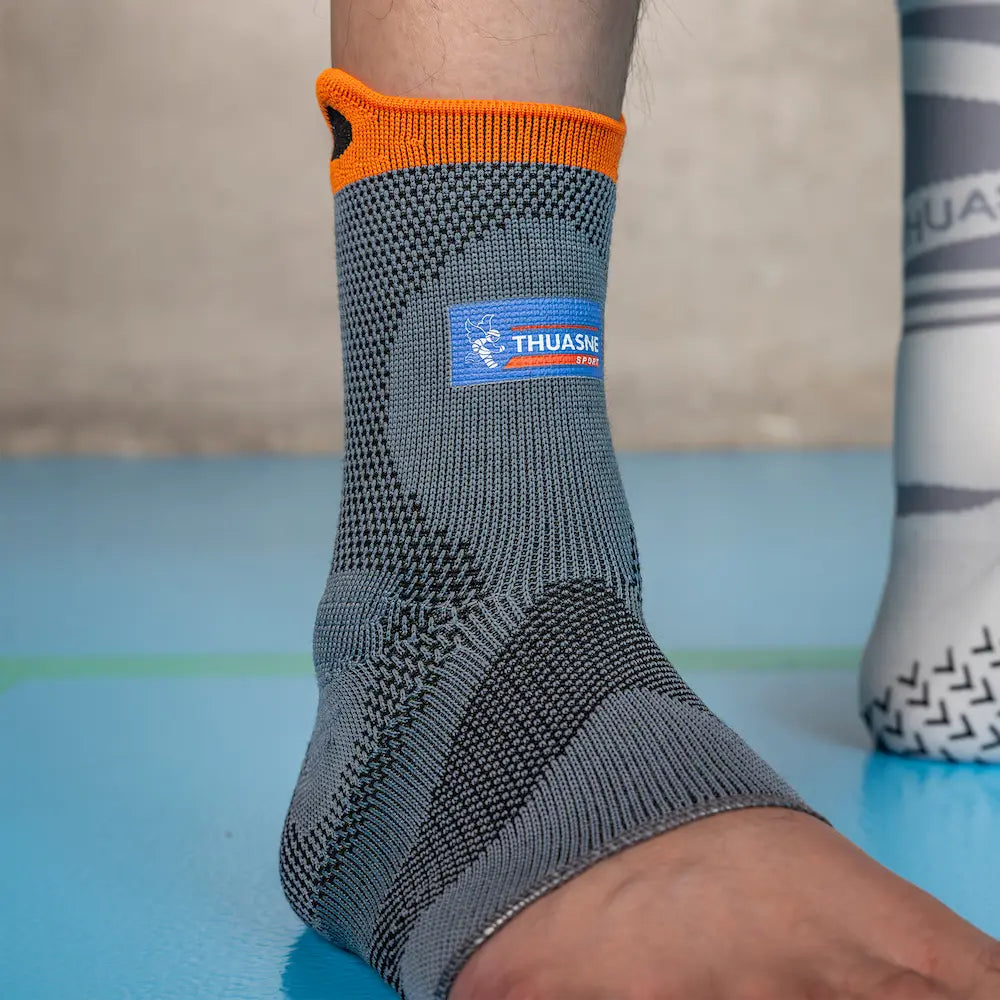 Chevillère de maintien renforcé Thuasne Sport Stabilité 3 grise portée, gros plan avec bordure orange et logo