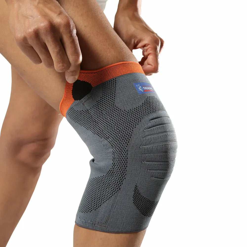 Genouillère de maintien renforcé Thuasne Sport Stabilité 3 grise portée, gros plan sur le tricot et la bordure orange