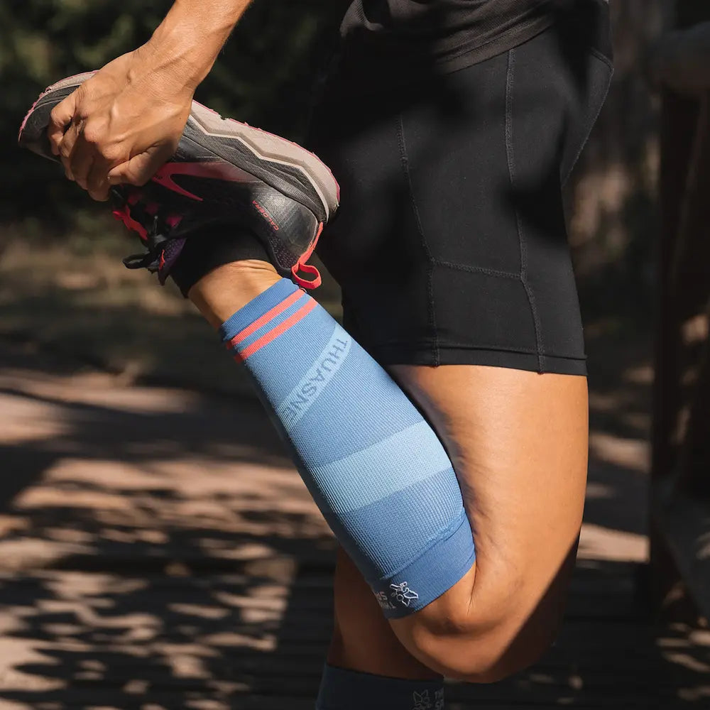 Femme en étirement portant un manchon de compression ACTIV Thuasne Sport bleu